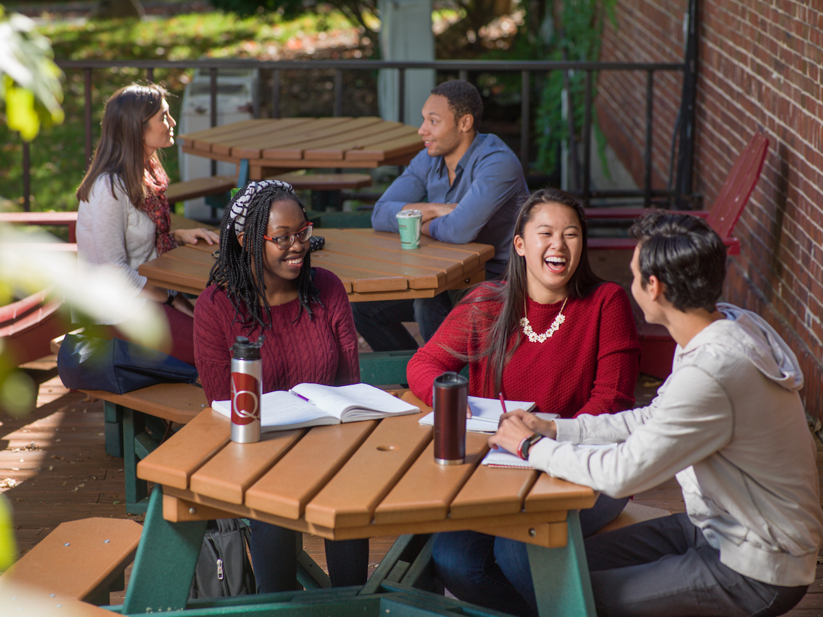 Students talking and smiling at a picnic table outside