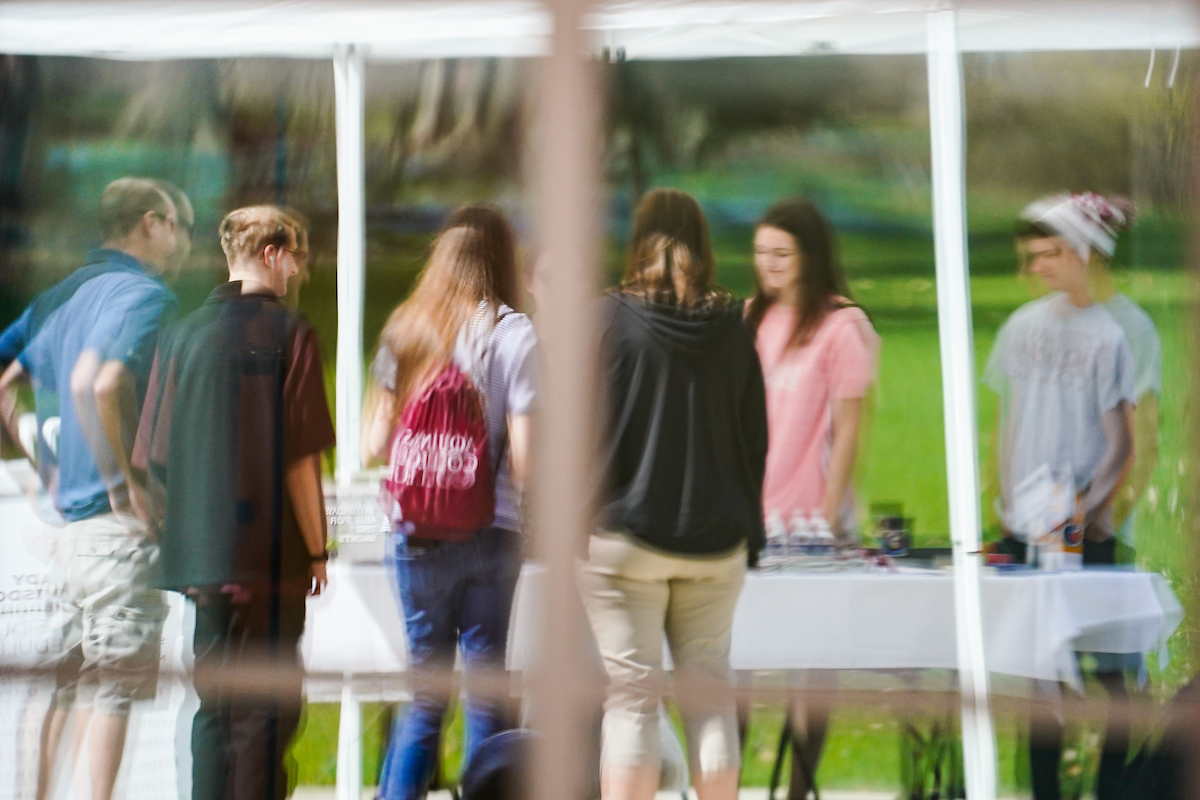 a Reflection on a window of students gathered at a table talking 