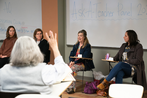 Ask a teacher panel sits at the front of the room while an audience member raises their hand