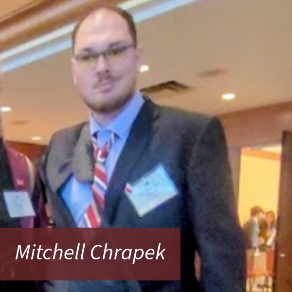 Photo of a man with glasses in a suit. Text Reading: Mitchell Chrapek