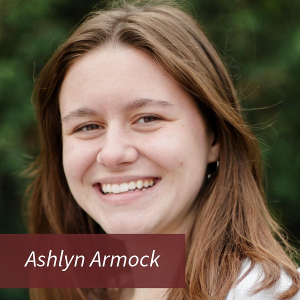 Headshot of a girl with shoulder length, light brown hair, standing outside. Text reading: Ashlyn Armock, Writing Center Consultant.