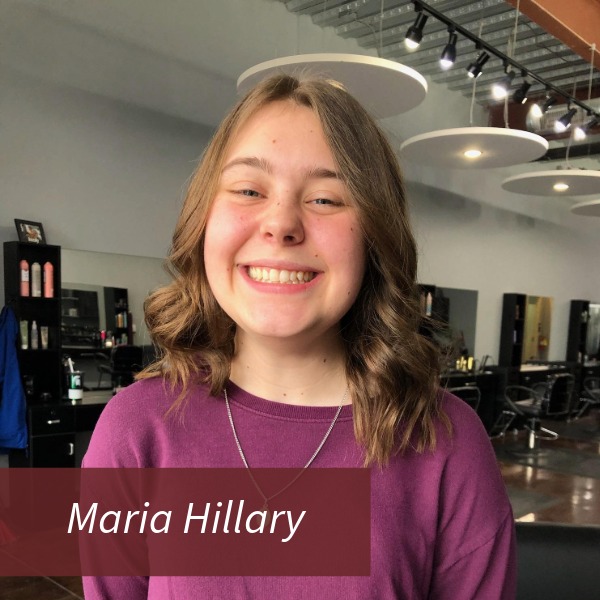 Picture of a girl with shoulder length hair, wearing a purple shirt, in a hair salon. Text reading: Maria Hillary, Writing Center Consultant.