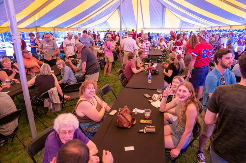 People of all ages gathering in the Aquinas College Homecoming tent, September 2025