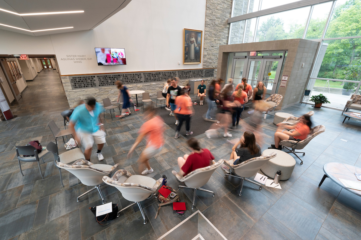 Students blurred by motion in a circle of chairs in the lobby of the science building
