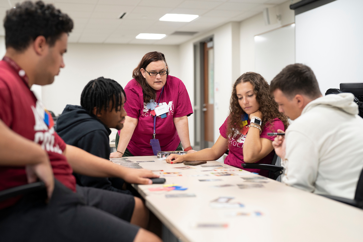 Students and professor looking intently at cards on a table