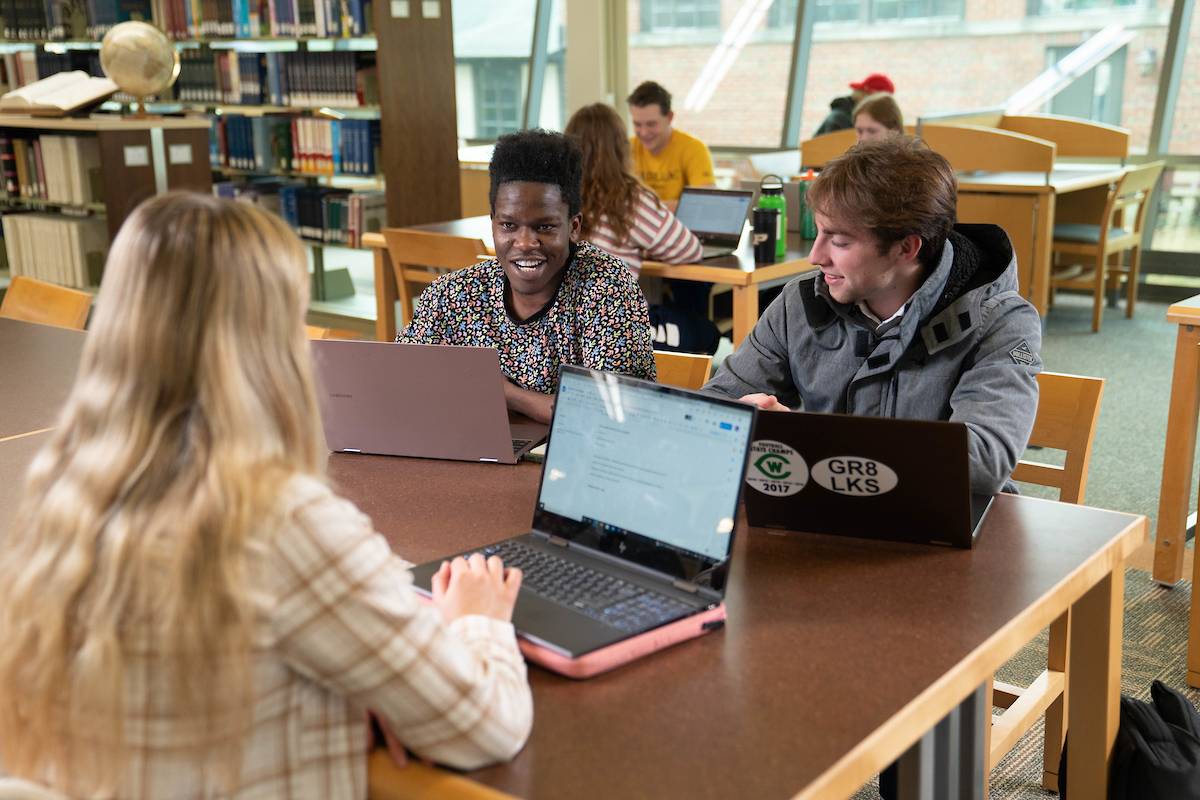 Students at a table with laptops talking