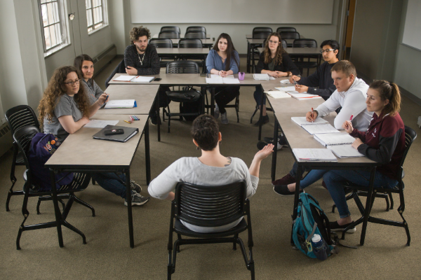 Students in small classroom gathered in a rectangle with desks