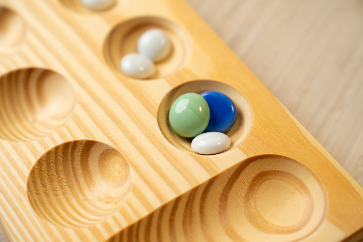 Mancala stones in pits on a Mancala board.