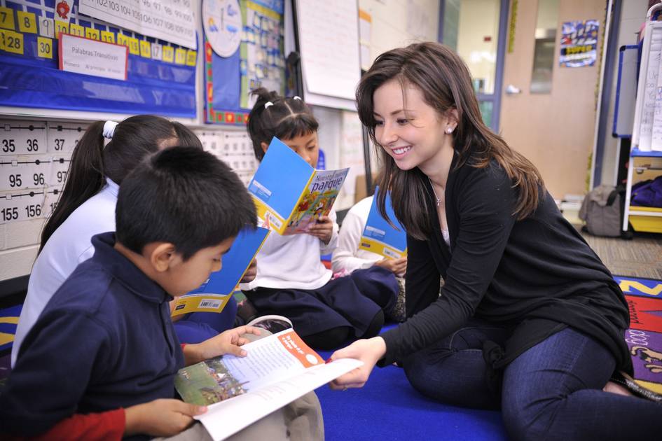 student helping children read in a classroom